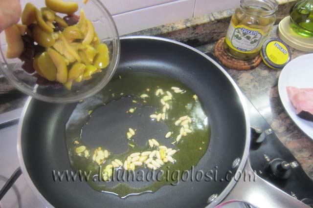 in una padella scalda l'olio d'oliva , soffriggi l'aglio insieme ai pinoli e aggiungi le olive denocciolate e tagliate