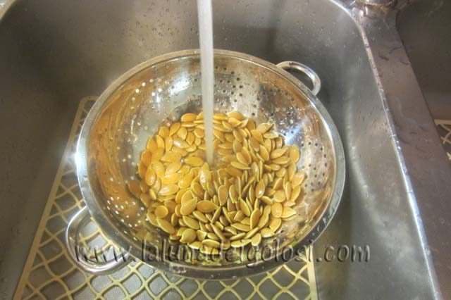 lava bene i semi di zucca sotto l'acqua corrente