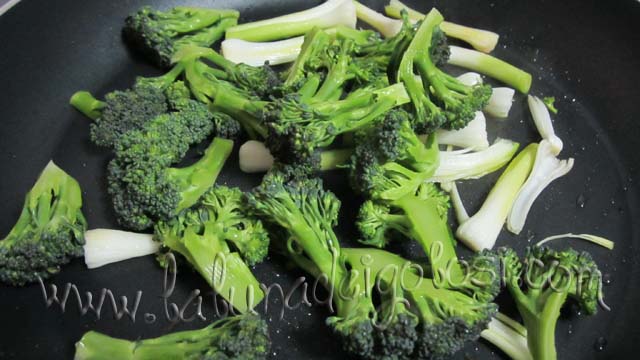 Poi metti l'olio nella padella, quando è caldo aggiungi la parte bianca dell'aglio tenero e le cimette dei broccoli