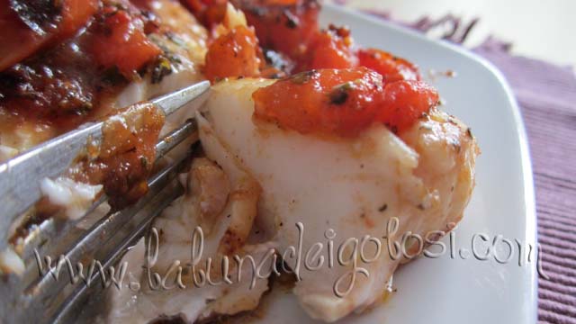 Metti il pesce nel piatto e ricoprilo con i pomodori, guarnisci con prezzemolo e, se necessario, aggiusta di sale